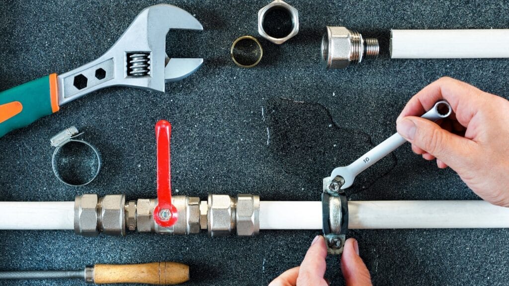 Plumber repairing a pipe valve with an adjustable wrench in Panama City Beach