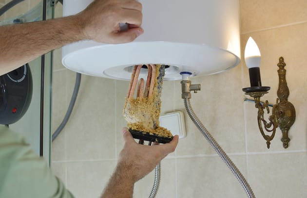 Technician removing mineral buildup from a water heater in Panama City Beach